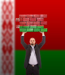 Image showing Businessman holding a large piece of a brick wall