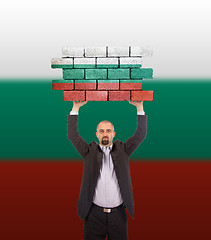 Image showing Businessman holding a large piece of a brick wall