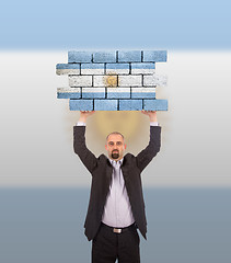 Image showing Businessman holding a large piece of a brick wall