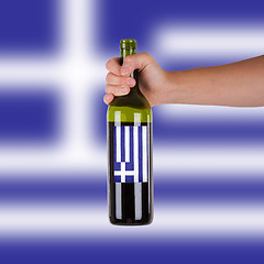 Image showing Hand holding a bottle of red wine