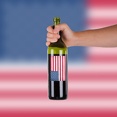 Image showing Hand holding a bottle of red wine