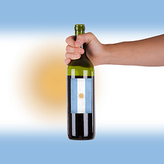 Image showing Hand holding a bottle of red wine