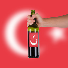 Image showing Hand holding a bottle of red wine