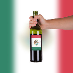 Image showing Hand holding a bottle of red wine