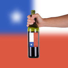 Image showing Hand holding a bottle of red wine