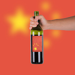 Image showing Hand holding a bottle of red wine