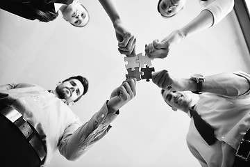 Image showing Group of business people assembling jigsaw puzzle