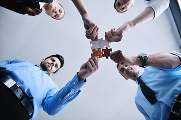 Image showing Group of business people assembling jigsaw puzzle