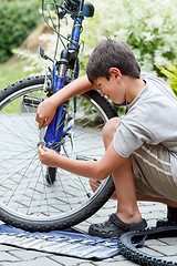 Image showing Teenager repairing his bike, changing broken tyre