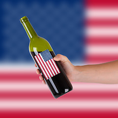 Image showing Hand holding a bottle of red wine