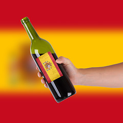 Image showing Hand holding a bottle of red wine