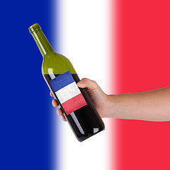 Image showing Hand holding a bottle of red wine