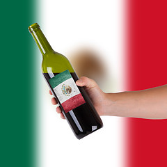 Image showing Hand holding a bottle of red wine