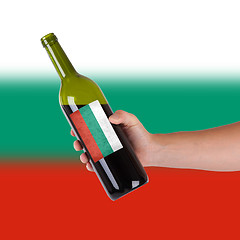 Image showing Hand holding a bottle of red wine