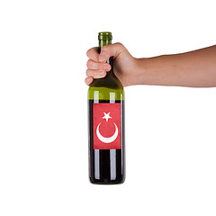 Image showing Hand holding a bottle of red wine