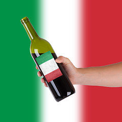 Image showing Hand holding a bottle of red wine