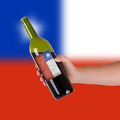 Image showing Hand holding a bottle of red wine