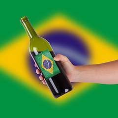 Image showing Hand holding a bottle of red wine