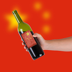 Image showing Hand holding a bottle of red wine