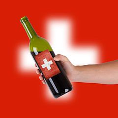 Image showing Hand holding a bottle of red wine