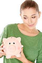 Image showing Woman giving her piggy bank a speculative look