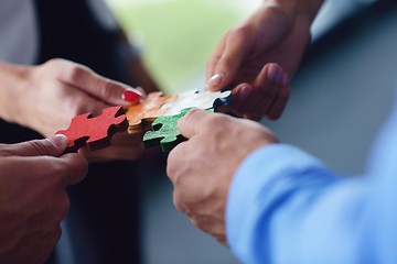 Image showing Group of business people assembling jigsaw puzzle