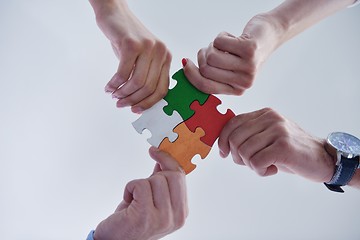 Image showing Group of business people assembling jigsaw puzzle