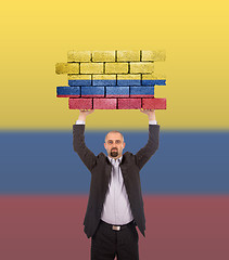 Image showing Businessman holding a large piece of a brick wall