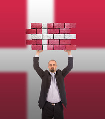 Image showing Businessman holding a large piece of a brick wall