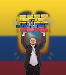 Image showing Businessman holding a large piece of a brick wall