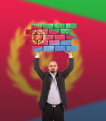 Image showing Businessman holding a large piece of a brick wall