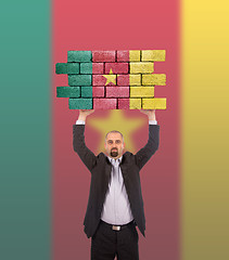 Image showing Businessman holding a large piece of a brick wall