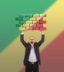 Image showing Businessman holding a large piece of a brick wall