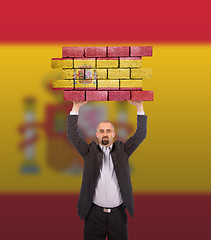 Image showing Businessman holding a large piece of a brick wall