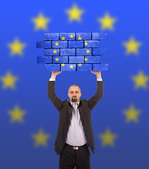 Image showing Businessman holding a large piece of a brick wall