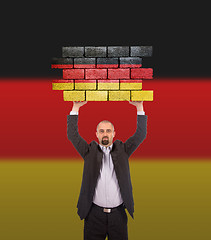 Image showing Businessman holding a large piece of a brick wall