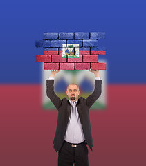 Image showing Businessman holding a large piece of a brick wall