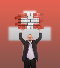 Image showing Businessman holding a large piece of a brick wall