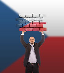 Image showing Businessman holding a large piece of a brick wall