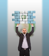 Image showing Businessman holding a large piece of a brick wall