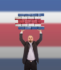 Image showing Businessman holding a large piece of a brick wall