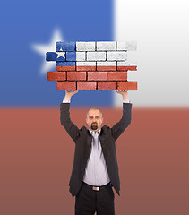 Image showing Businessman holding a large piece of a brick wall