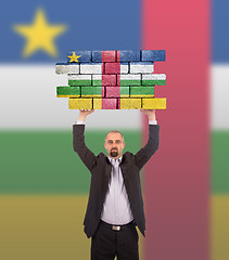 Image showing Businessman holding a large piece of a brick wall