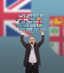 Image showing Businessman holding a large piece of a brick wall