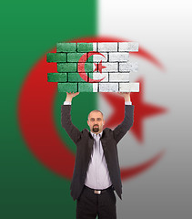 Image showing Businessman holding a large piece of a brick wall