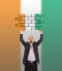 Image showing Businessman holding a large piece of a brick wall