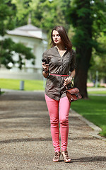 Image showing Young Woman Walking in a Park with a Mobile Phone