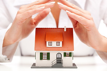 Image showing Female hands saving small house with a roof