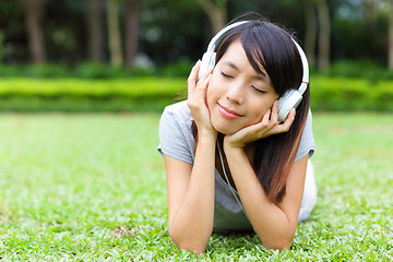 Image showing Asian woman listen to song lying on grass