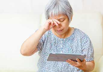 Image showing Asian old woman using digital tablet with tired eyes